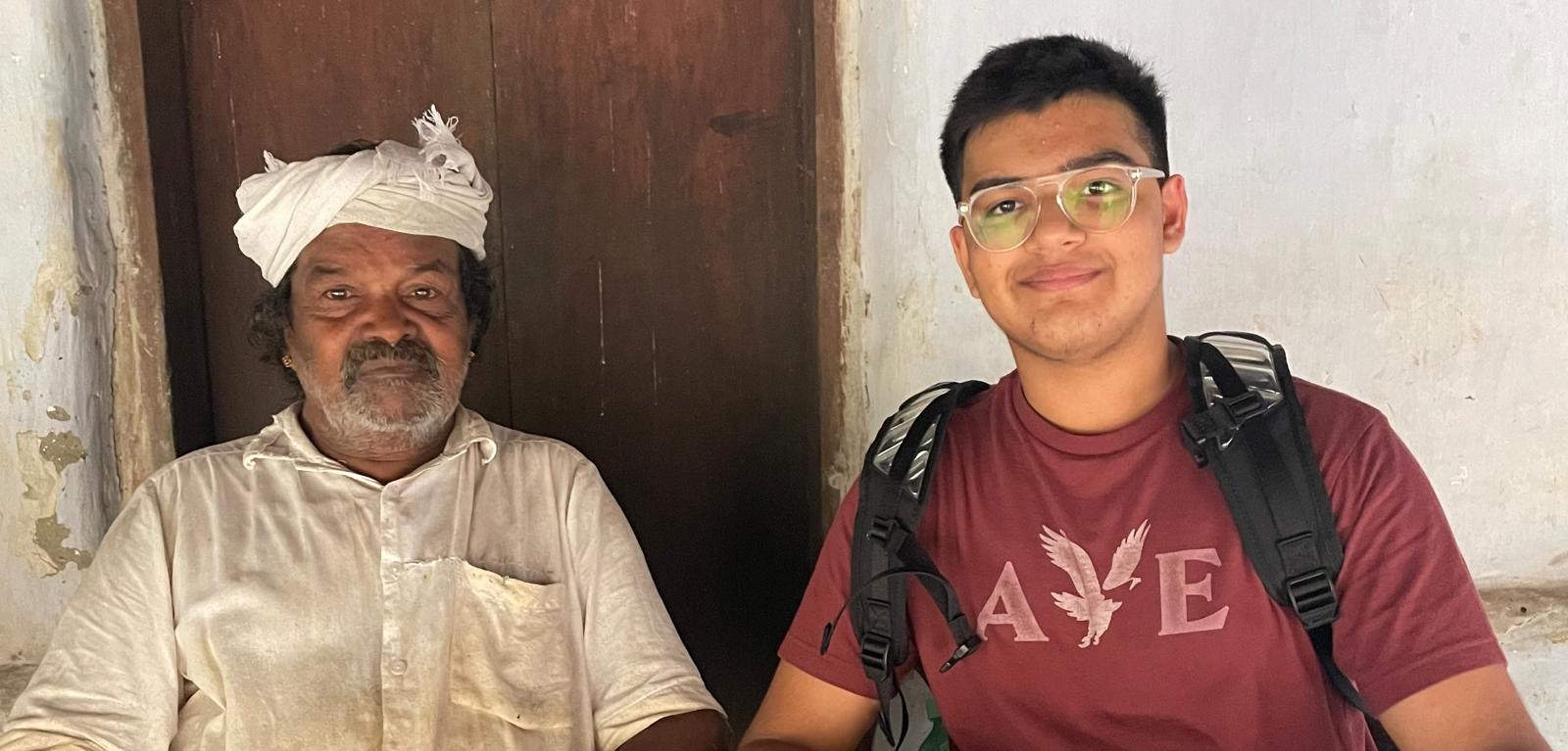 Aveer sitting beside seed keeper Cheruvayal Raman outside his home